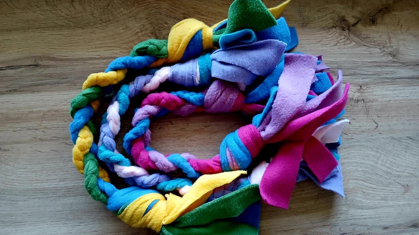 A colorful, braided rope made of soft felt fabric in various shades including blue, yellow, pink, purple, and green.